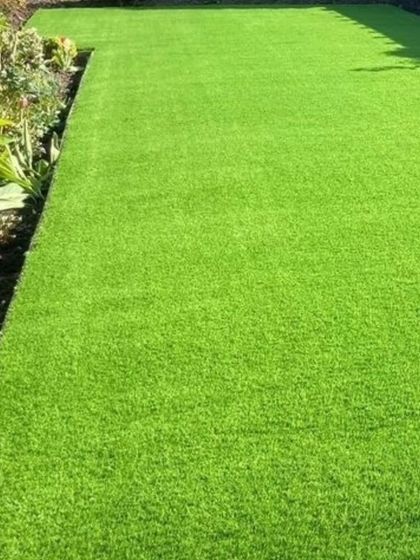 A freshly laid patch of artificial grass in a garden setting. It provides a perfect, lush green lawn all year round, without the need for watering, pesticides, or mowing.