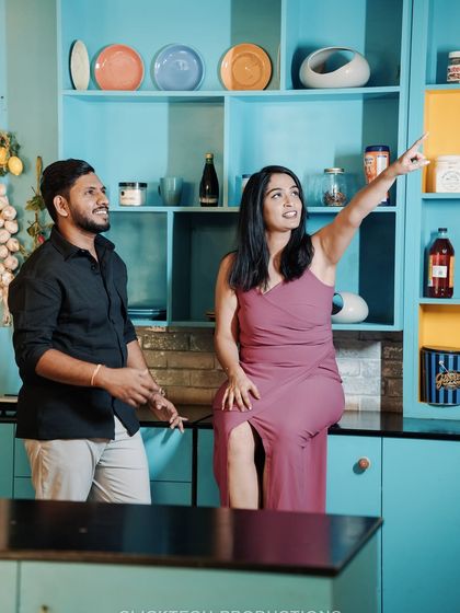 A fun, interactive shot of a couple in a brightly colored kitchen set, pointing at something off-camera.