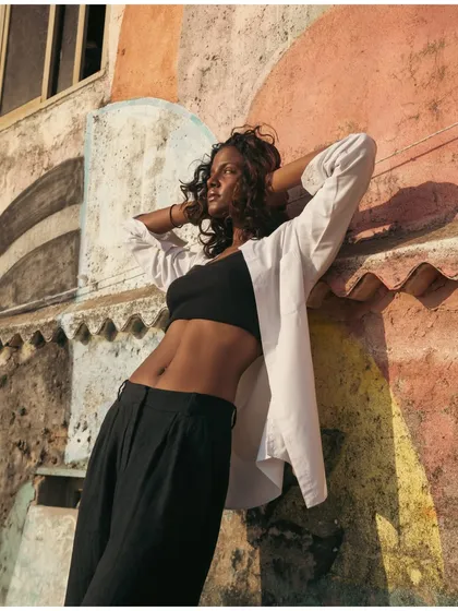 A different angle of the model against the graffiti wall, showcasing her toned physique and the interesting textures of the location.