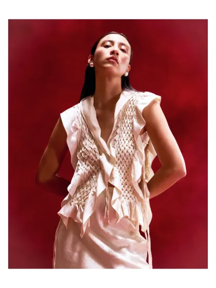 This unique white top with textured ruffles and fringe details is a statement piece. It’s for the woman who appreciates artistry and confidence in her style.
