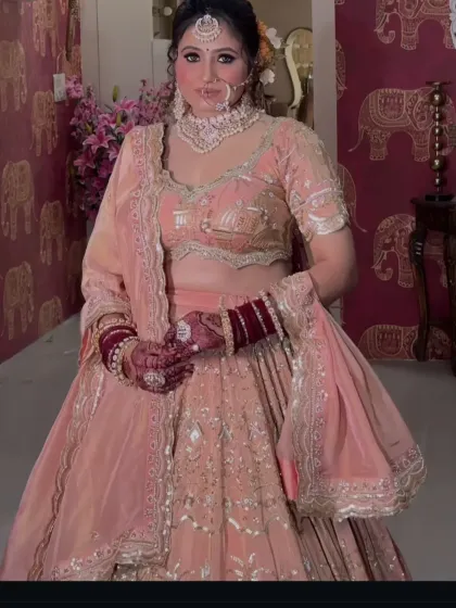 A close-up of the peach-pink lehenga, focusing on the blouse embroidery and the bridal jewelry.