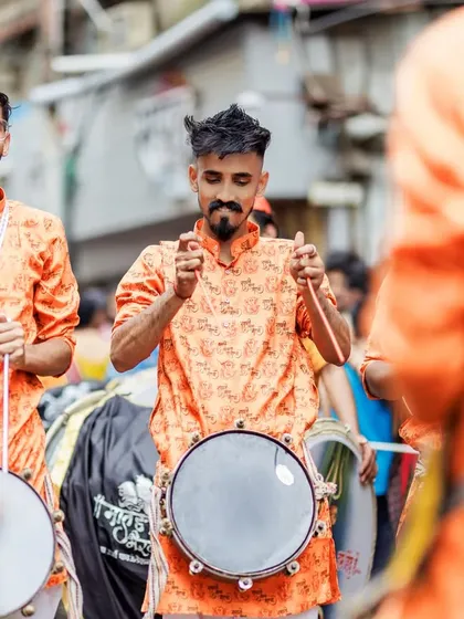 A tasha player, focused on the rhythm, surrounded by his fellow musicians.