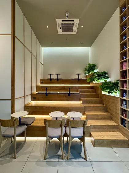 A straight-on view of the stepped seating, showing the symmetry and order in the design. The combination of wood, grey cushions, and subtle lighting creates a comfortable and visually appealing space for customers.