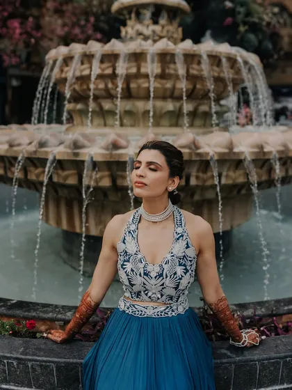 A serene portrait of the bride-to-be, sitting by a fountain during her pre-wedding celebration.