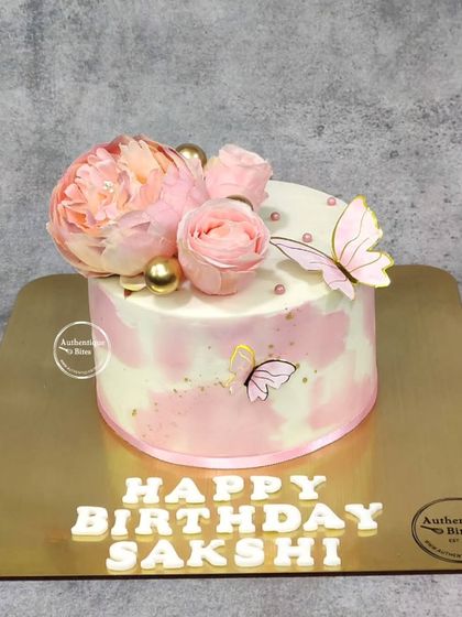A delicate butterfly floral cake. The soft pink and white watercolor effect is complemented by beautiful peonies and fluttering butterflies.