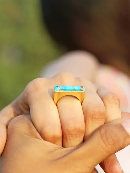 A romantic and intimate shot focusing on a bold, turquoise-colored statement ring on a model's hand. This type of image tells a story and creates an emotional connection with the product.