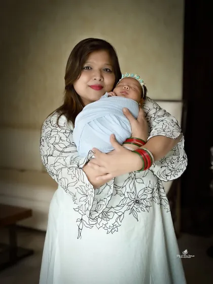 A simple and elegant portrait of a mother holding her swaddled newborn. Her gentle smile and the baby's peaceful sleep make for a beautiful and classic mother-child photo.