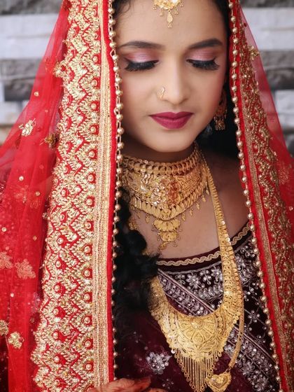 A beautiful portrait of a Muslim bride. Her makeup features a soft pink and gold eye look, paired with a deep red lip, all framed by a stunning red and gold dupatta.