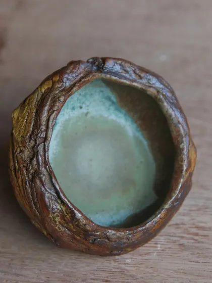 Another view of the small, textured bowl. The combination of foraged materials, slips, and glazes creates a surface that is rich and complex.