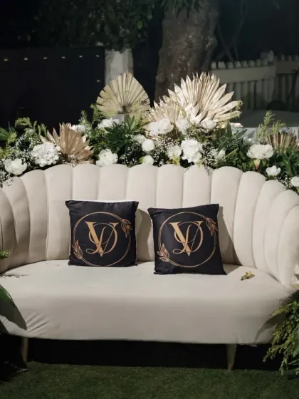The happy couple deserves a special spot. We created this elegant seating area for the bride and groom at their Sangeet, featuring a classic white sofa, lush floral arrangements, and custom monogrammed pillows.