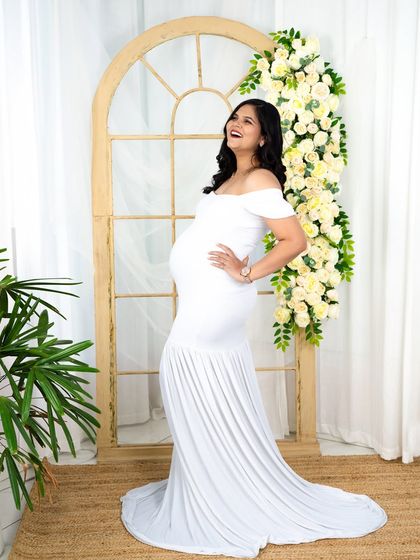 A joyful and candid moment captured in a classic white mermaid gown. The natural light and floral archway in our studio provide a fresh and uplifting backdrop.
