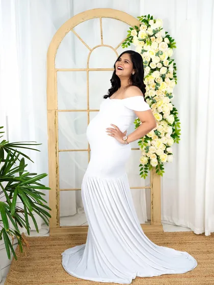 A joyful and candid moment captured in a classic white mermaid gown. The natural light and floral archway in our studio provide a fresh and uplifting backdrop.