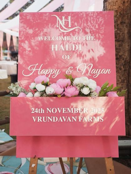 Personalization is key. This custom welcome sign for Happy and Nayan's Haldi ceremony uses a beautiful font and a floral accent box, perfectly matching the event's pink-themed decor.