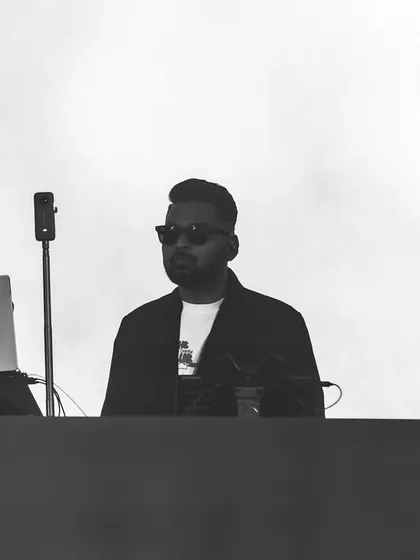 A stark, black and white photo from a festival set. This minimalist shot highlights the silhouette and focus of a DJ at work.