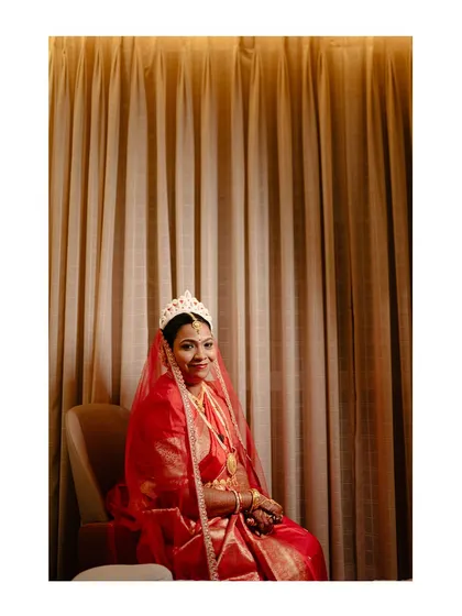 A full-length portrait of the bride in her stunning red and gold Benarasi saree, the epitome of Bengali bridal grace.