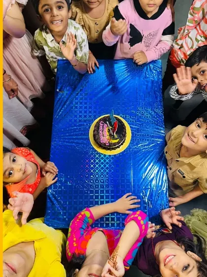 A top-down view of the kids gathered around the anniversary cake. These moments of shared joy are what make our community special.