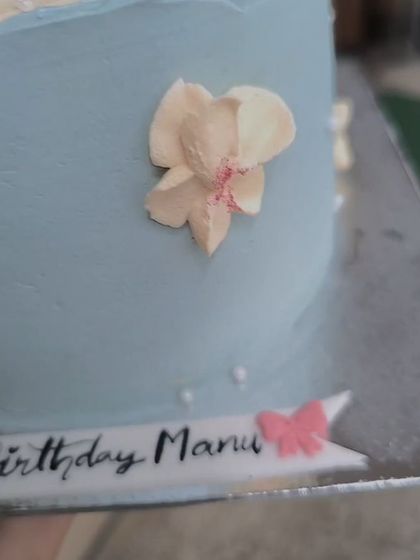 A close-up showing the delicate, hand-piped buttercream florals on this pale blue aesthetic cake. The color palette and design are just perfect.