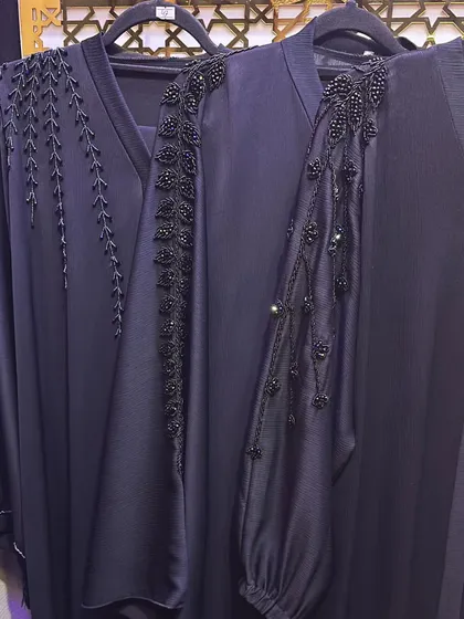 The sleeve details on these dark navy abayas are incredible. One features a climbing vine of black beads, while the other has a more abstract floral beadwork design.