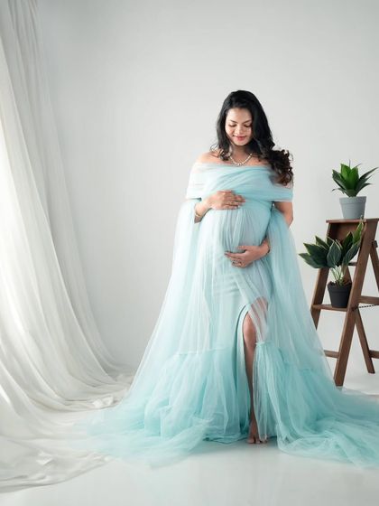 A full-length portrait showcasing a gorgeous light blue gown. The simple props and bright lighting keep the focus on the mom-to-be and her radiant glow.