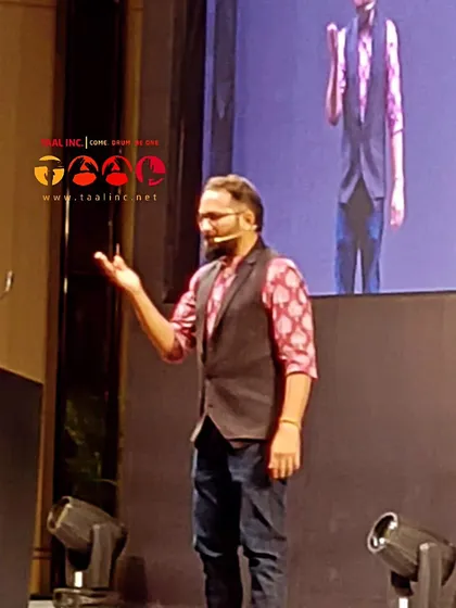 A facilitator is a guide. Here, our facilitator is using hand gestures to guide the group's rhythm during an interactive corporate drumming session.