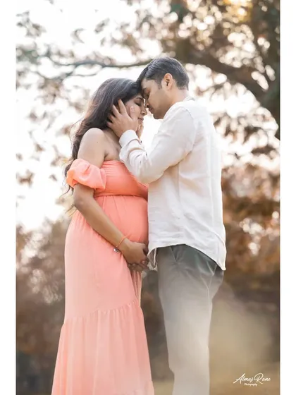 A tender moment between expecting parents, framed by the soft light of the outdoors. This image focuses on their closeness and the shared anticipation of welcoming their third family member.