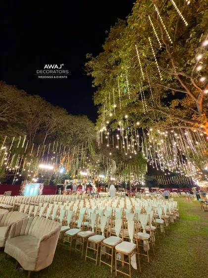 A stunning night view of the extensive guest seating, with rows of chairs illuminated by a sky of hanging fairy lights.
