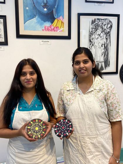 Two friends with their finished dot mandala pieces. It's a great activity to do together, as you can chat while you create.