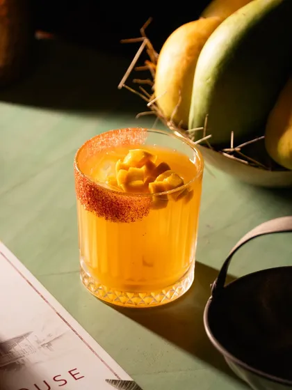 A mango cocktail with a chili-dusted rim. The combination of sweet and spicy is communicated visually through the garnish and color.