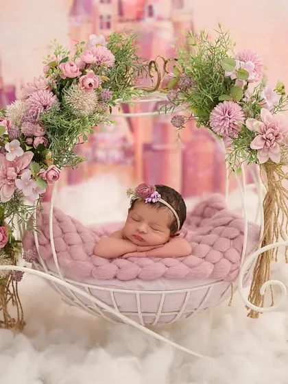 A true fairy tale scene, where a sleeping baby girl rests in a beautiful floral carriage, floating on a bed of clouds with a dreamy castle in the background.