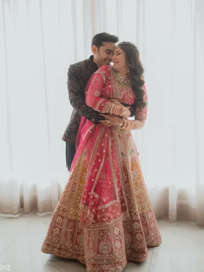 A warm and intimate embrace from behind, captured against soft, natural light from a window. This photo perfectly encapsulates the feeling of comfort and love between the couple.