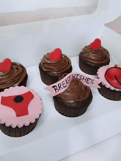 A box of naughty-themed cupcakes with "Breast Wishes" for the bride-to-be.