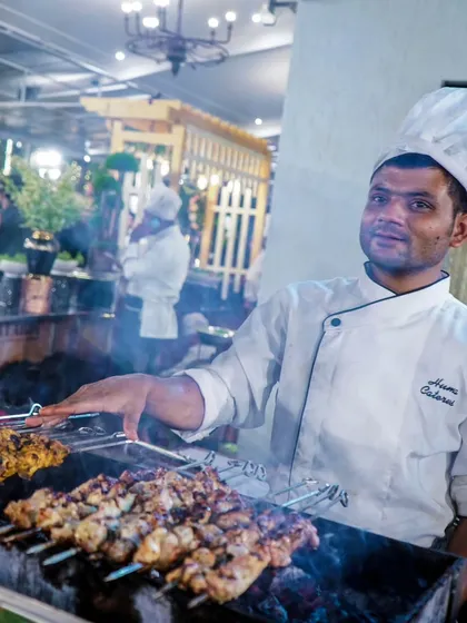 Our chef proudly grilling marinated meat skewers at an outdoor event. We bring the full tandoor and BBQ experience to your venue.