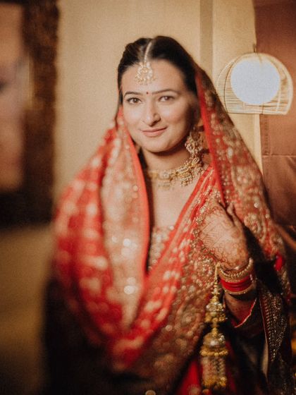 A soft, gentle portrait of the bride, Ankita, her warm smile and beautiful red dupatta creating a timeless image.