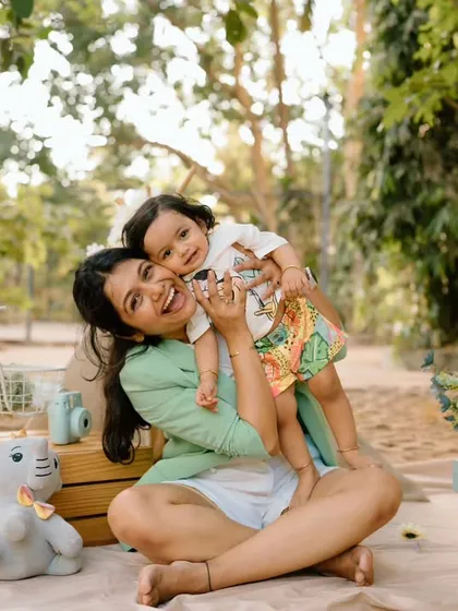 Another beautiful, interactive pose from the same mother-child session, showcasing the loving and playful bond they share amidst a charming picnic setup.