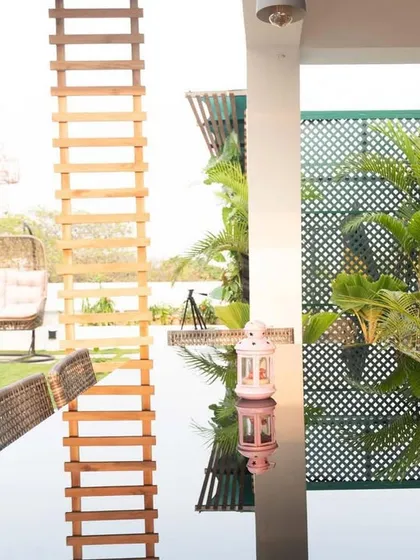A closer look at the dining area in this terrace garden. The reflection on the glass tabletop beautifully mirrors the green privacy screen and the sky, making the space feel open and connected to the outdoors.