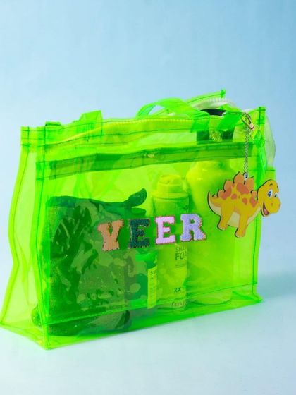 A neon green jelly chic bag, personalised with a name and a cute dinosaur charm.