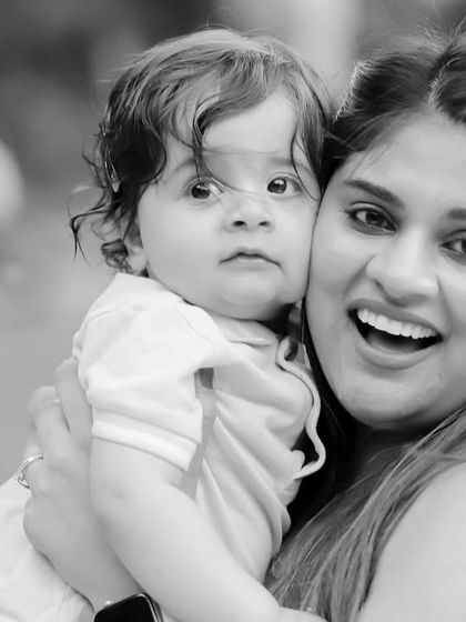 A close-up black and white portrait of a mother and her baby, highlighting their connection and happy expressions.