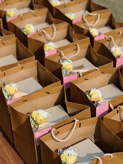 Our baby announcement gifts, elegantly placed in kraft paper bags. Each bag is adorned with a small floral bouquet, adding a touch of nature to the presentation.