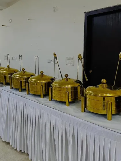 Our catering rental services include high-quality equipment like these elegant brass chafing dishes and food warmers, perfect for adding a royal touch to your buffet line.