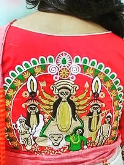 The back of a custom embroidered blouse for Durga Puja. This red blouse features a detailed, colorful depiction of Maa Durga with her children, making it a standout piece.