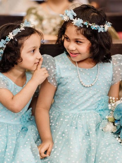 A sweet moment between two flower girls. They are wearing matching light blue dresses with polka dots, and I created their blue and white floral head wreaths to complete their adorable look.