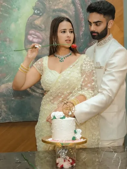 A joyous cake-cutting moment during an indoor engagement celebration in Pune. The couple's happiness is the focus, framed by modern decor and a beautiful piece of art, capturing the celebratory spirit of the occasion.