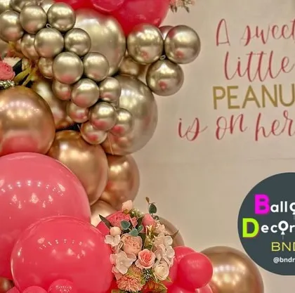 A vibrant baby shower theme for a baby girl, using hot pink and metallic balloons with the message "A sweet little peanut is on her way!".