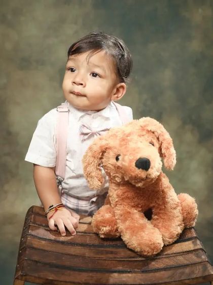 A classic toddler portrait. His thoughtful expression and the vintage-style backdrop give this photo a timeless, painterly quality.