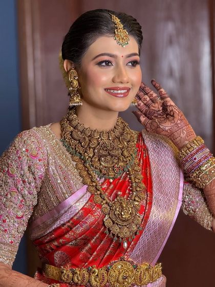 A happy bride ready for her Muhurtham. Her makeup features a warm, peachy eyeshadow and a radiant smile, capturing the joy of the moment.