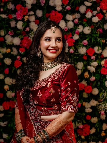 Sheetal's reception look, featuring a rich red velvet lehenga. I created a classic glam look with soft smokey eyes and a matching lip, set against a beautiful floral backdrop.