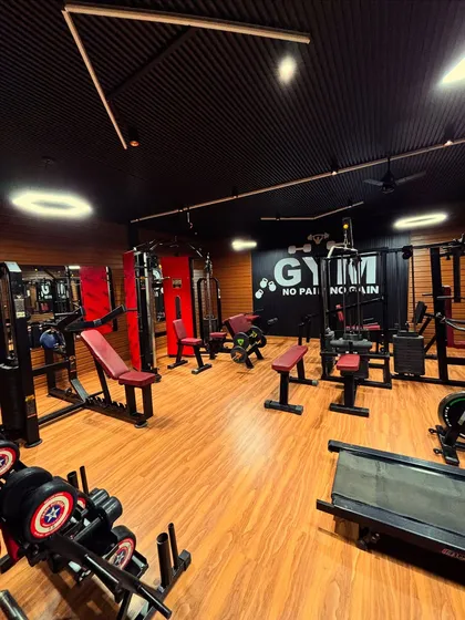 This shot captures the overall layout of the personal gym. You can see the dumbbell rack in the foreground and various strength training machines arranged to create a complete workout circuit. The lighting design includes both functional spotlights and ambient ring lights.