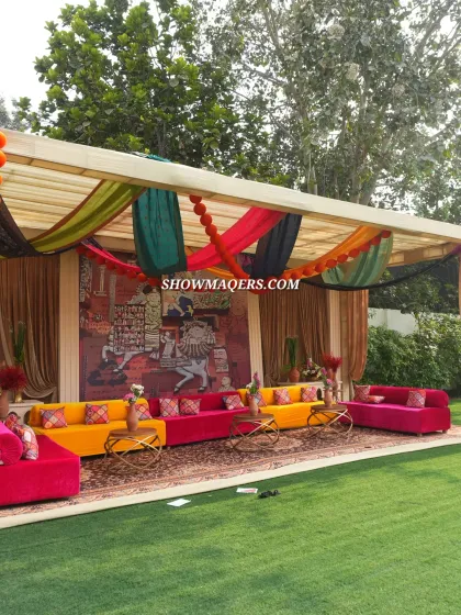 A vibrant lounge area from our Banaras-themed event, featuring brightly colored sofas in pink and yellow, set against a traditional mural backdrop.