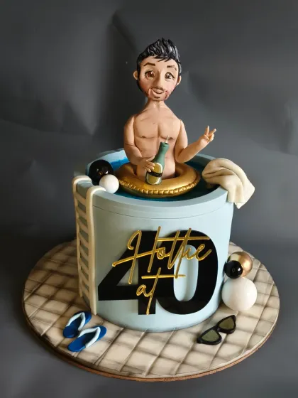 Celebrating a 40th birthday in style! This "Hottie at 40" cake features a custom figurine of the birthday boy chilling in a hot tub with a bottle of bubbly. The tiled floor and scattered flip-flops complete this fun pool party scene.