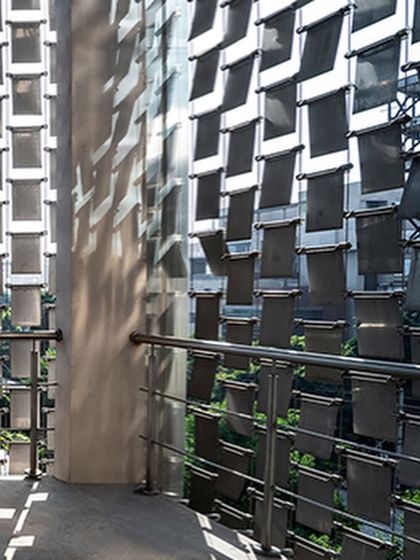 A detail shot of the 'shimmer screen,' showing how the individual steel panels are fixed to create a kinetic façade that casts moving shadows and reflects sunlight.